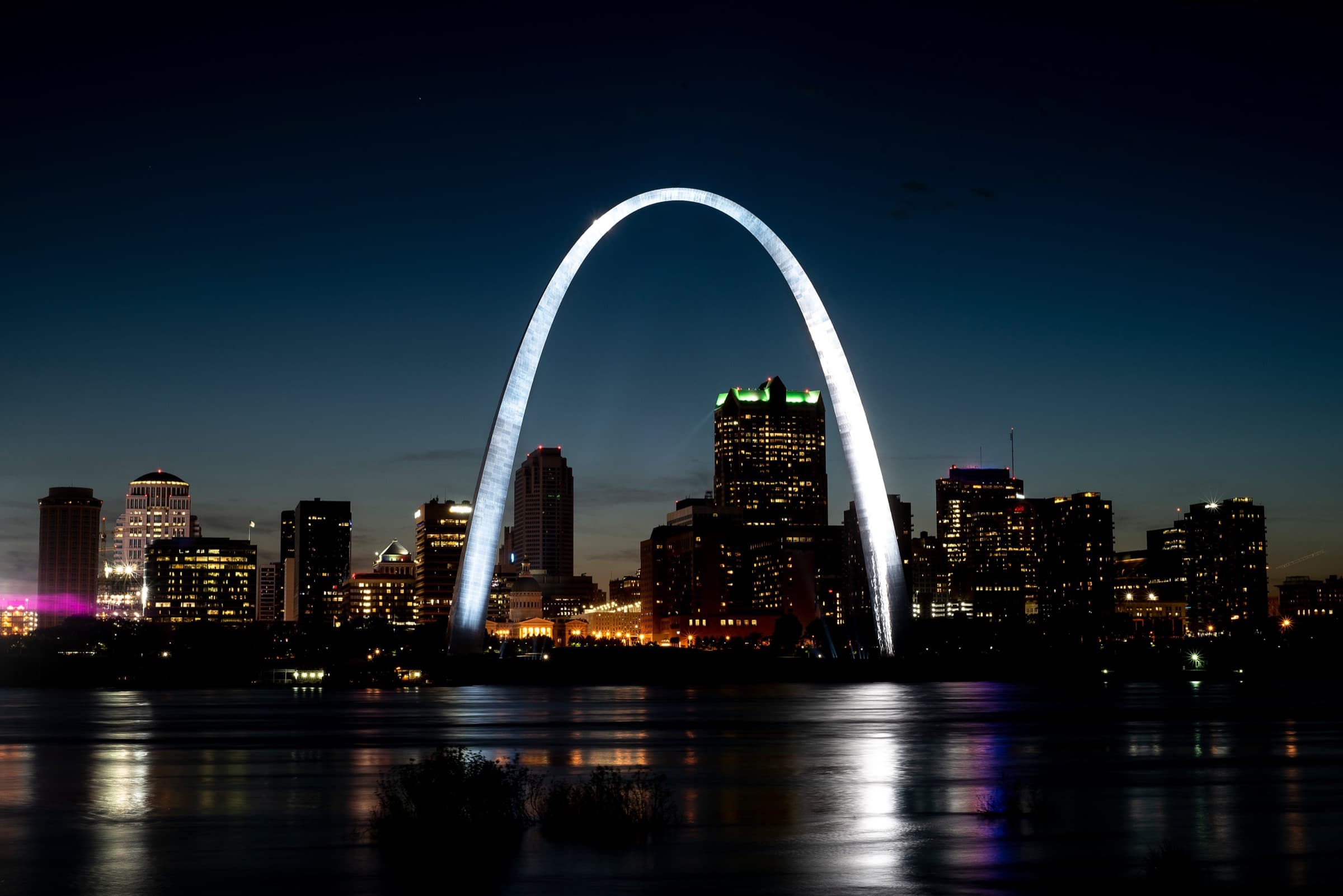The Gateway Arch and St. Louis skyline at night, reflected in the Mississippi River